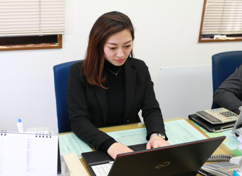 手帳とEメールでスケジュールのチェックを行う谷村 文