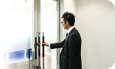 出社時にドアノブに手をかける加々美祐和