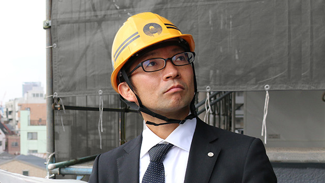 工事現場の壁を見上げる設計室スタッフ 加々美