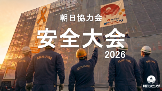 安全大会2026の文字と現場の足場を見上げる作業着姿の参加者たち